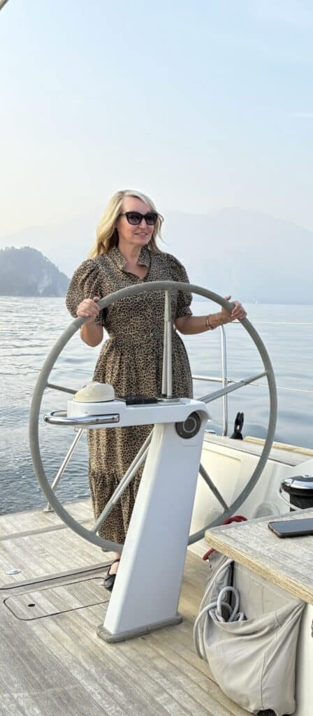 International Travel Agent Greta Meschke steering a yacht on Lake Como, representing Greta & Co. Travel Design’s expertise in luxury international travel experiences.